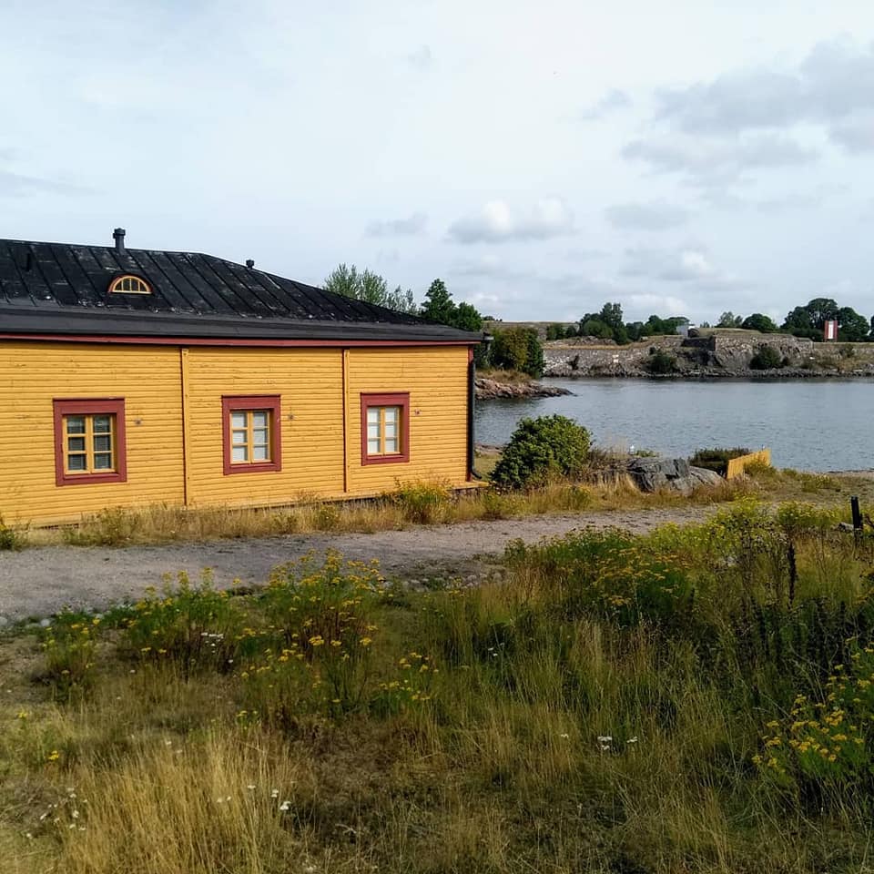 A yellow house by the sea with the fortress behind on Suomenlinna island in Helsinki